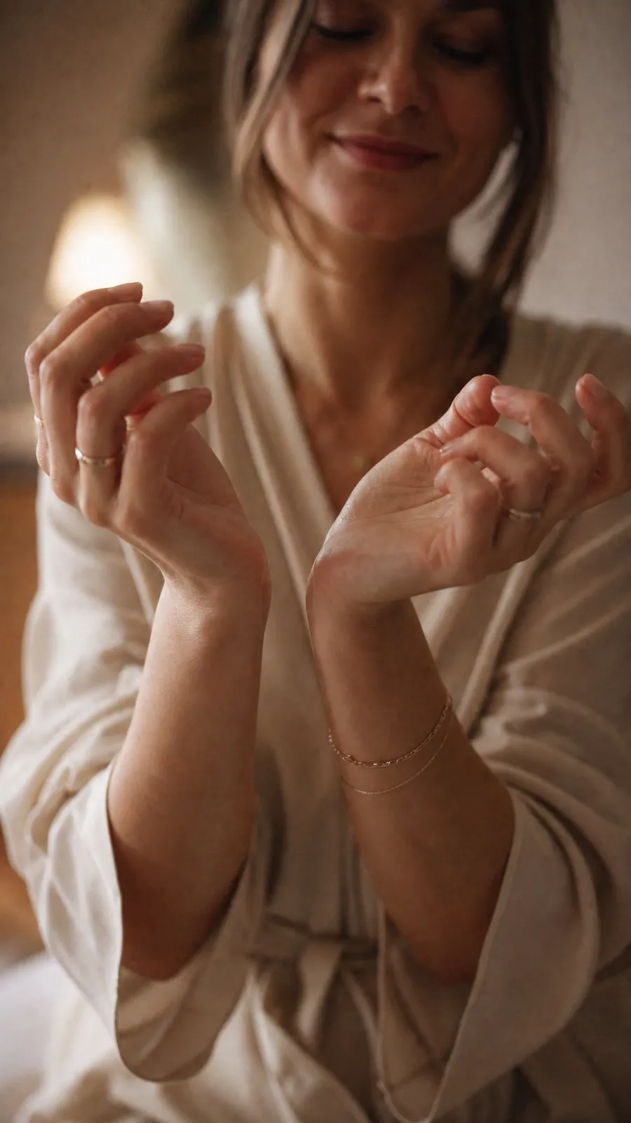 Two wrists lifted to the face after a drop of perfume, warm morning light